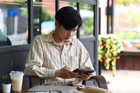 Handsome businessman sitting outdoor cafe and using smart phone.の写真素材