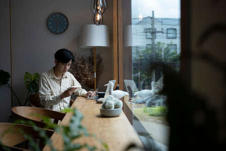 Young asian man sitting in cafe and using smart phone.の写真素材