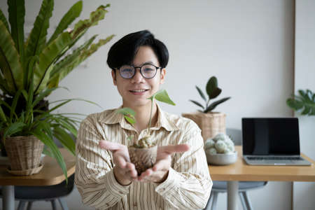 Handsome man small business entrepreneur holding potted plant and smiling to camera.の写真素材