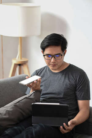 Young man freelancer working with computer tablet and talking on mobile phone at home.