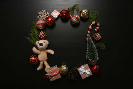 Christmas ornaments, gifts boxes, pine cone, teddy bear and fir tree branches decoration on dark background.の写真素材