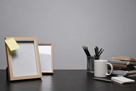 Empty picture frame, coffee cup and books on black wooden table.の写真素材