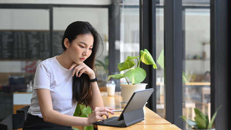 Charming young asian woman working online with computer tablet.の写真素材