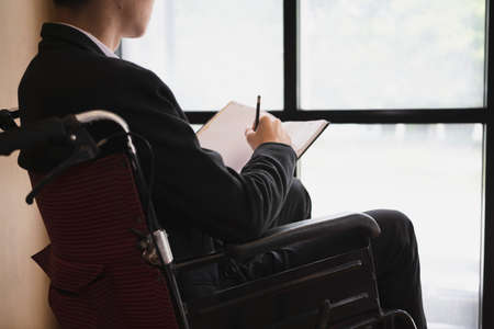 Thoughtful businessman in wheelchair working in the office.の写真素材