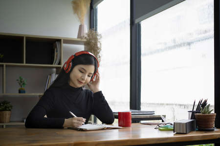 Young asian woman enjoy drinking coffee and listening to music with headphone.