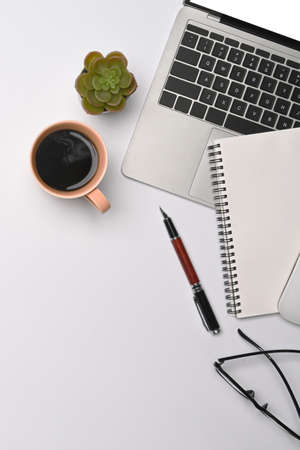 Top view laptop computer, coffee cup, notebook and glasses on white office desk.の写真素材