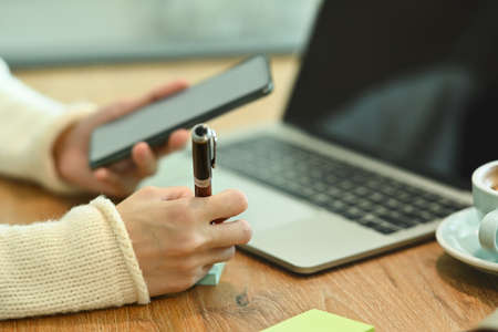 Smiling asian woman in white sweater using laptop computer in living room.の写真素材