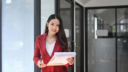Attractive businesswoman holding reports and looking at camera.