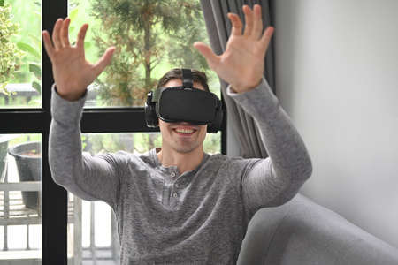 Young wearing virtual reality headset and playing video game or watching movie at home.