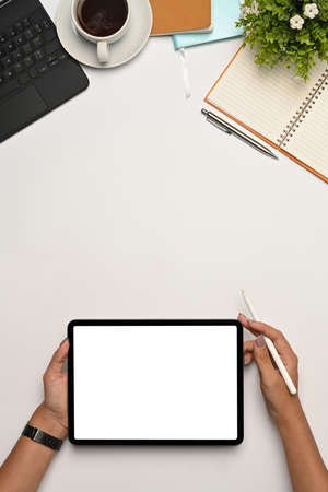 Overhead view young woman holding digital tale and stylus pen on white office desk.の写真素材