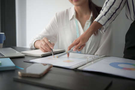 Two businesswoman analyzing financial reports together at office desk.の写真素材