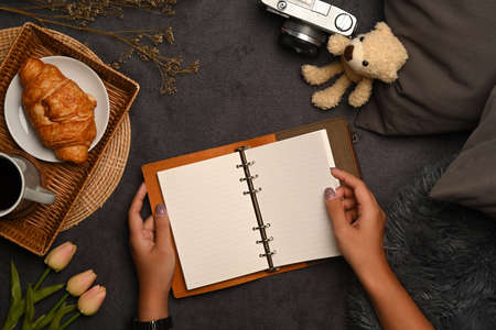 Young woman sitting on gray carpet and reading book.