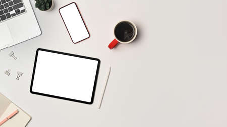 Above view digital tablet, smart phone and laptop computer on white office desk.