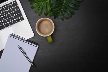 Stylish workspace with computer laptop, notebook and coffee cup on black table.の写真素材
