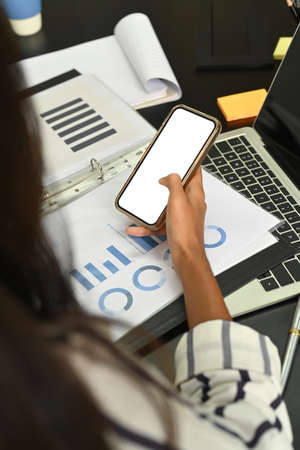 Cropped shot businesswoman sitting at her office desk and using smart phone.