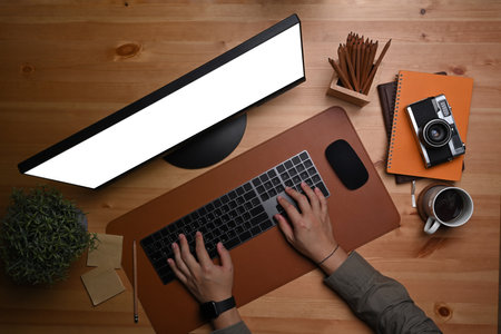 Man working with computer on wooden table in home office.の写真素材