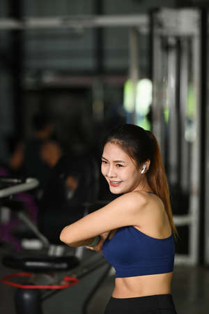 Smiling young woman warming up before workout in gym.の写真素材