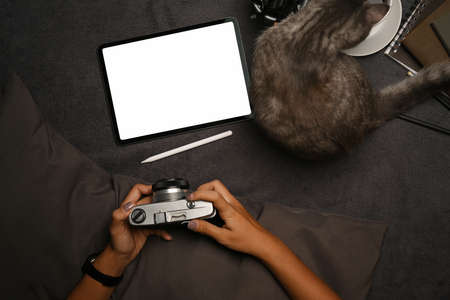 Above view woman holding camera and using digital tablet on carpet.の写真素材