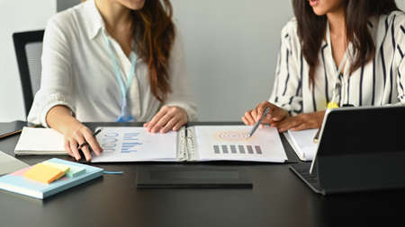 Two smiling women office workers working together in office.
