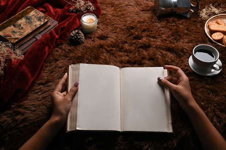 Woman holding book on fluffy carpet.の写真素材