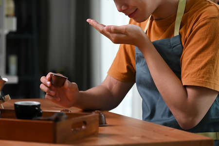 Young isn man using computer tablet and making coffee with a coffee machine.