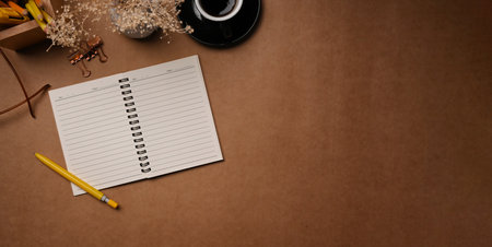 Top view empty notebook, coffee cup and eyeglasses on brown background.の写真素材