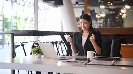 Excited businesswoman reading letter or notice with good news and celebrating her achievement.の写真素材
