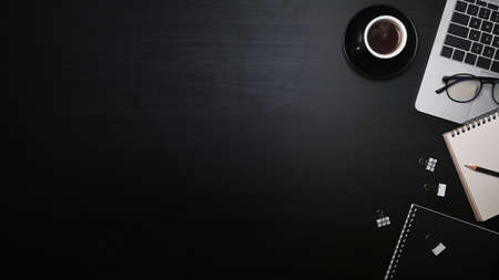 Top view laptop computer, notebook and cup of coffee on black wooden table.の写真素材