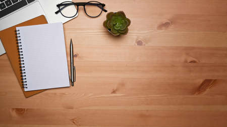 Empty notepad, glasses and laptop computer on wooden table.