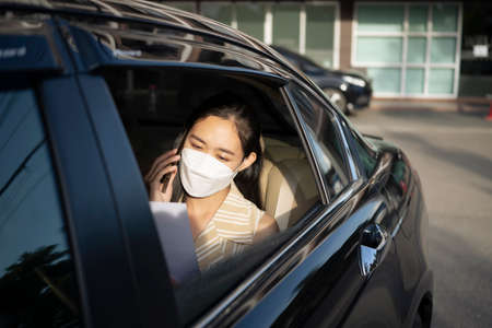 Young asian woman talking on mobile phone while sitting in a taxi.の写真素材
