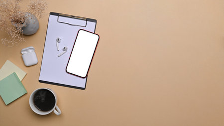 Smart phone with blank screen and laptop computer on beige background.の写真素材