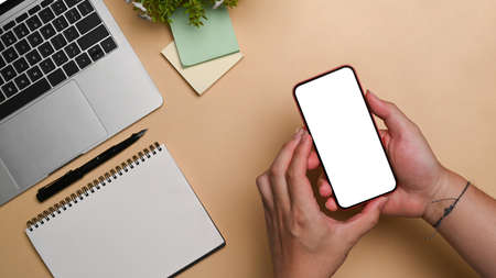 Overhead view young man holding smart phone with empty display.