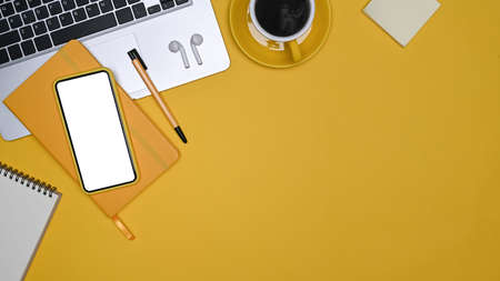 Above view mock up smart phone, laptop computer and notebook on yellow background.の写真素材