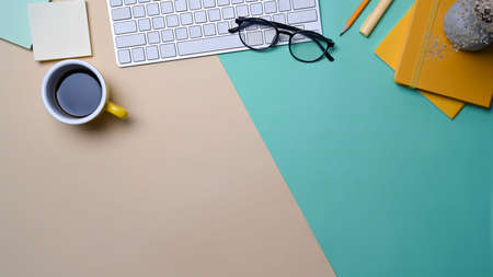 Top view wireless keyboard, coffee cup and notebook on colorful background.の写真素材