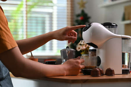 Cropped shot young man making coffee with a coffee machine in the kitchen.