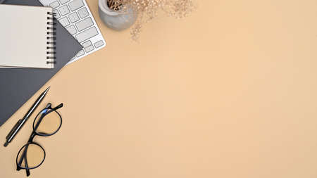 Above view eyeglasses, notebook and keyboard on beige background.