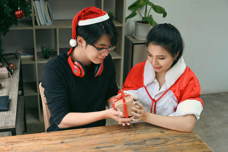 Young couple opening Christmas gift and celebrating Christmas at home.