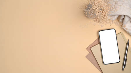 Top view smart phone, notebook and pen on beige background.の写真素材