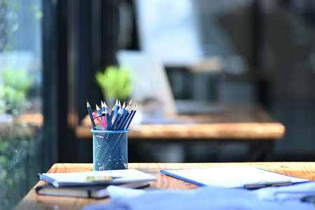 Pencil holder, books and financial documents on wooden table in office.の写真素材