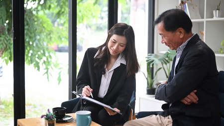 Elderly man consulting with health insurance agent. Senior health insurance concept.の写真素材