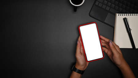 Top view mobile phone, clipboard and coffee cup on black table.
