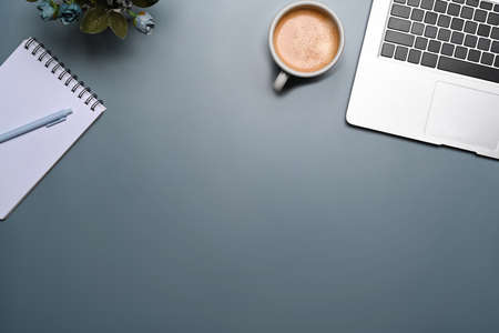 Computer laptop, coffee cup glasses and notebooks on gray background. Copy space.