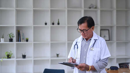 Mature doctor in white medical uniform working in hospital.の写真素材