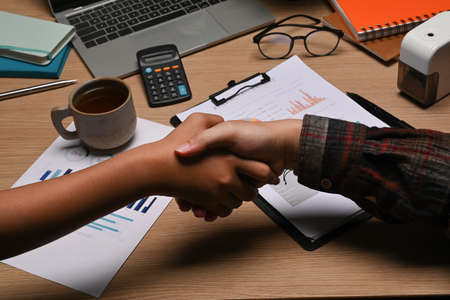 Cropped shot business people shaking hands after finishing contract signing in office.