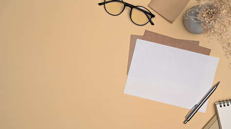 Top view blank paper card, sticky note and glasses on beige background.の写真素材