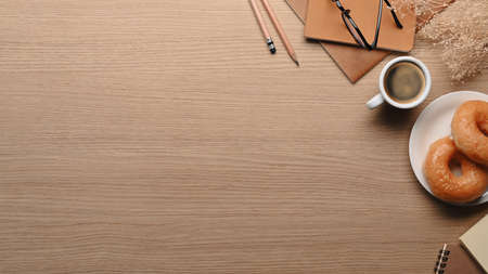 Above view tasty donuts cup of coffee and notebooks on wooden table.の写真素材