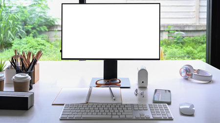 Front view computer with empty display and office supplies on white table.