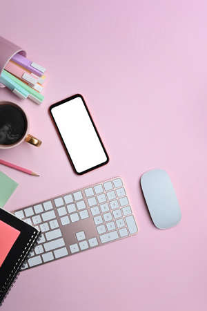 Above view mobile phone, keyboard and stationery on pink background.の写真素材