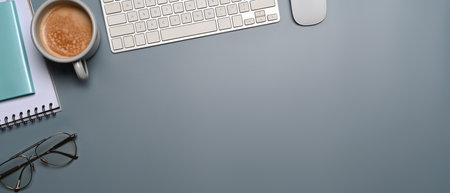 Top view coffee cup, glasses, notebook and wireless keyboard on blue background.の写真素材