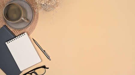 Top view notebook, eyeglasses and cup of coffee on beige background.の写真素材
